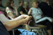 Two people sitting in church, one holding the others hand supportively