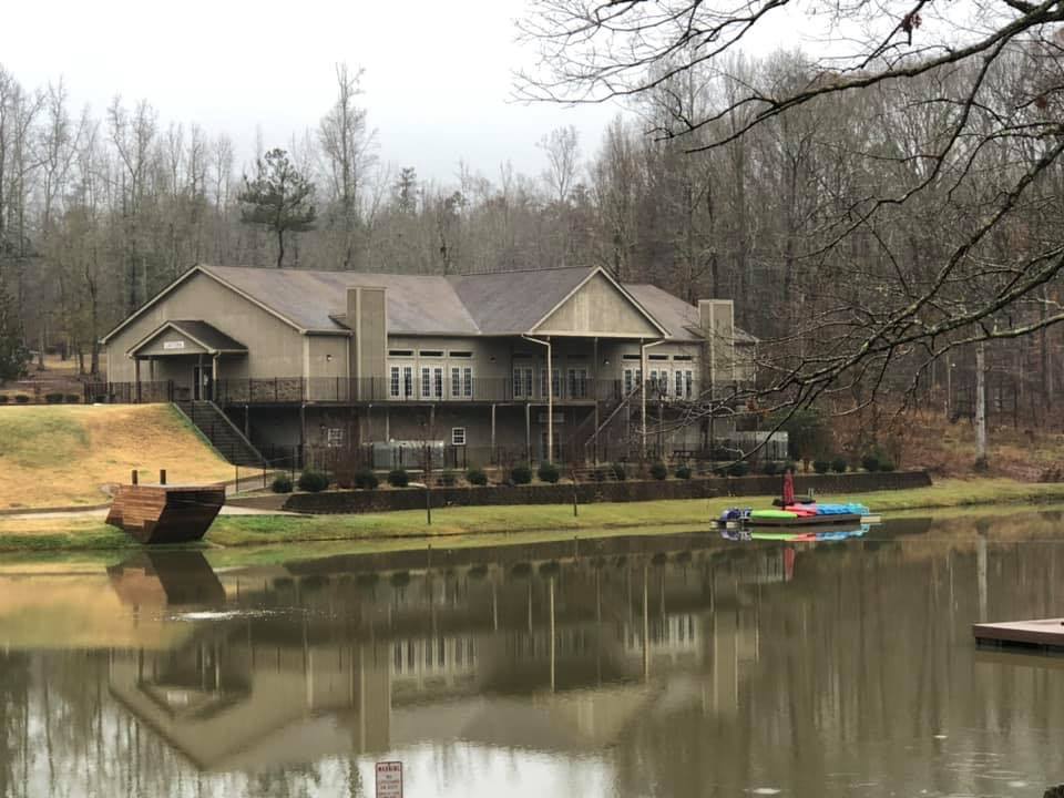 Large building in the woods on a quiet lake with boats in the water